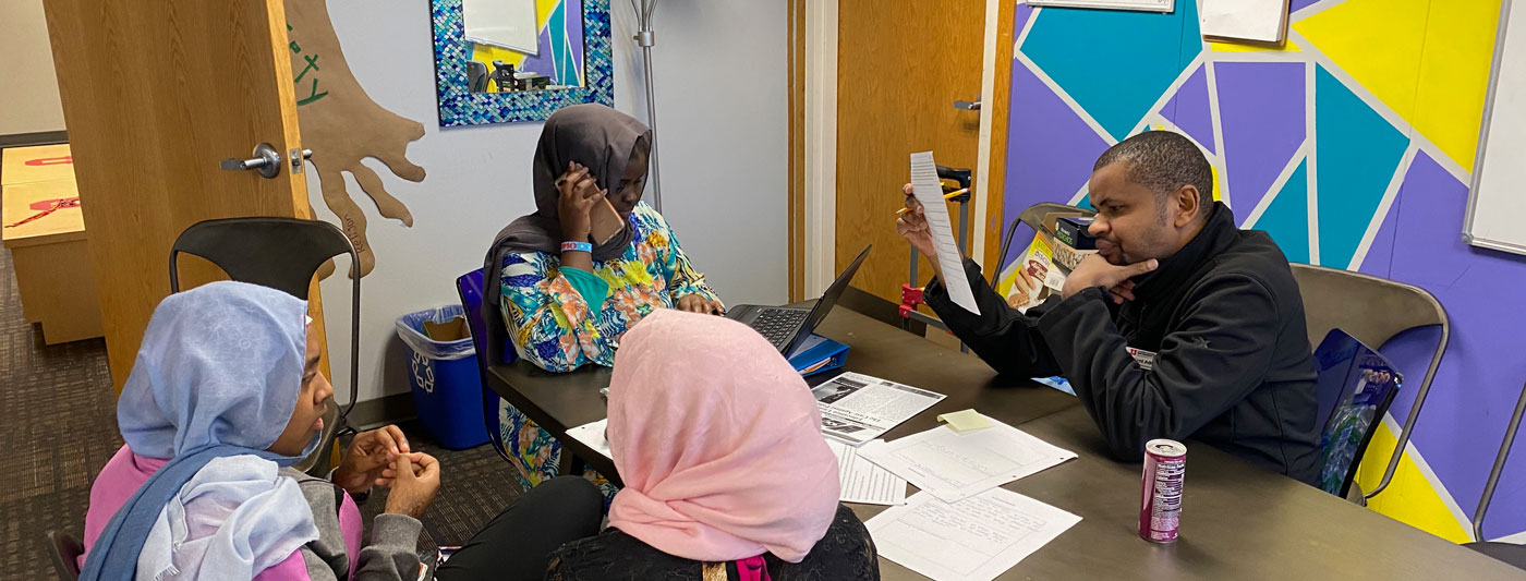 Three youth in head scarves and an adult around a table