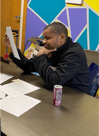 Jeilani sitting at table reading a piece of paper